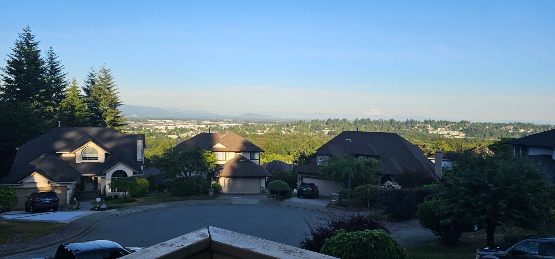 A roof with a vent on it and a building in the background.