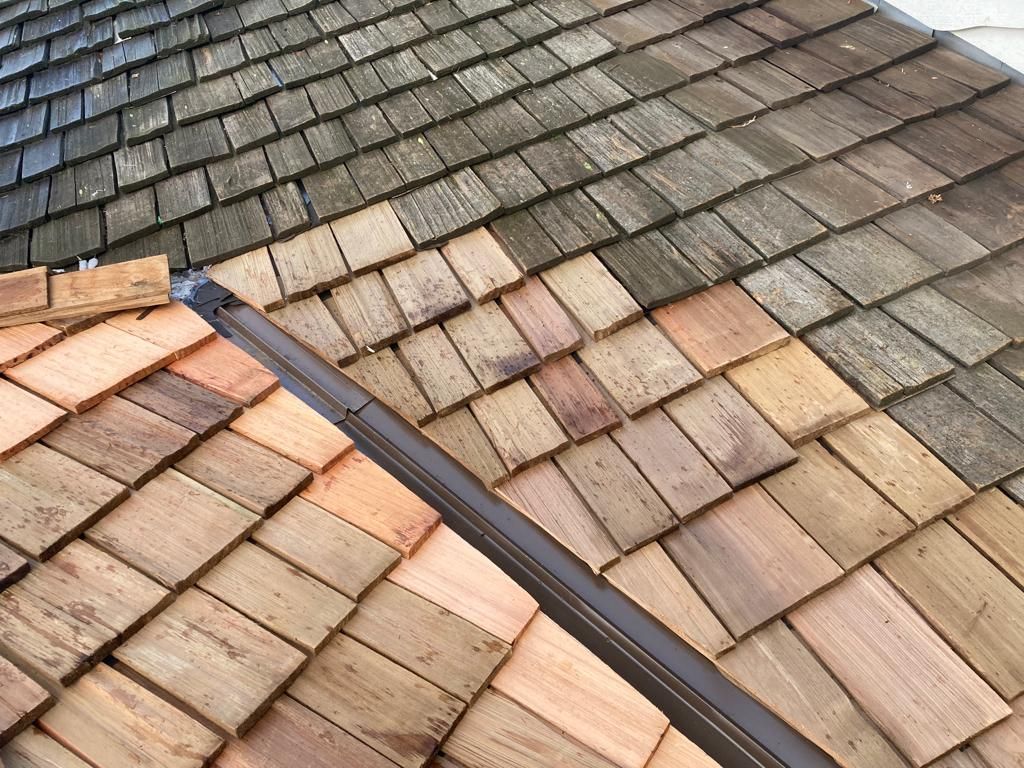 A close up of a wooden roof with different colored tiles.