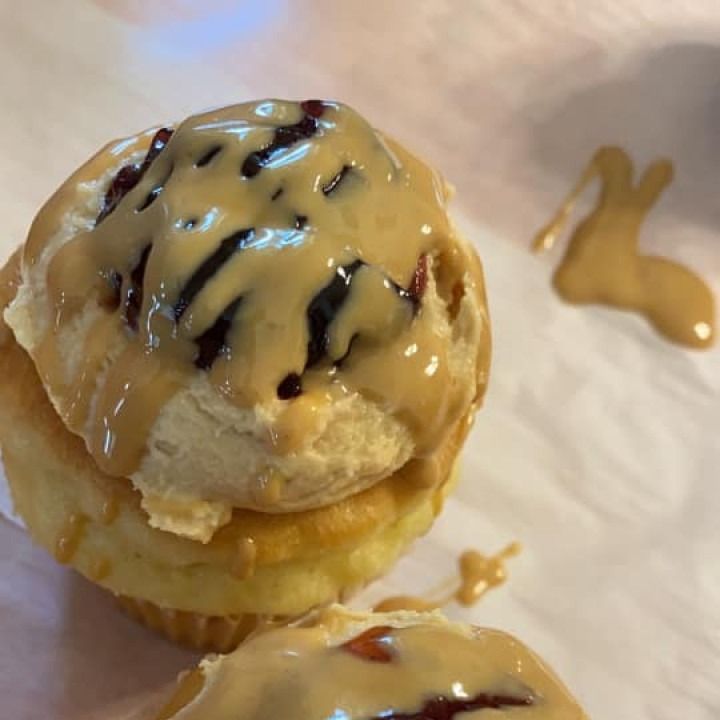 Cinnamon roll with peanut butter glaze, stacked on a second roll, on parchment paper.