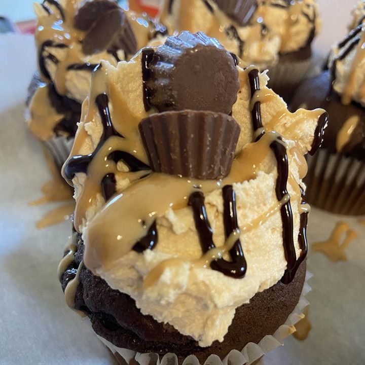 Chocolate cupcakes topped with peanut butter frosting, Reese's cups, caramel, and chocolate drizzle.