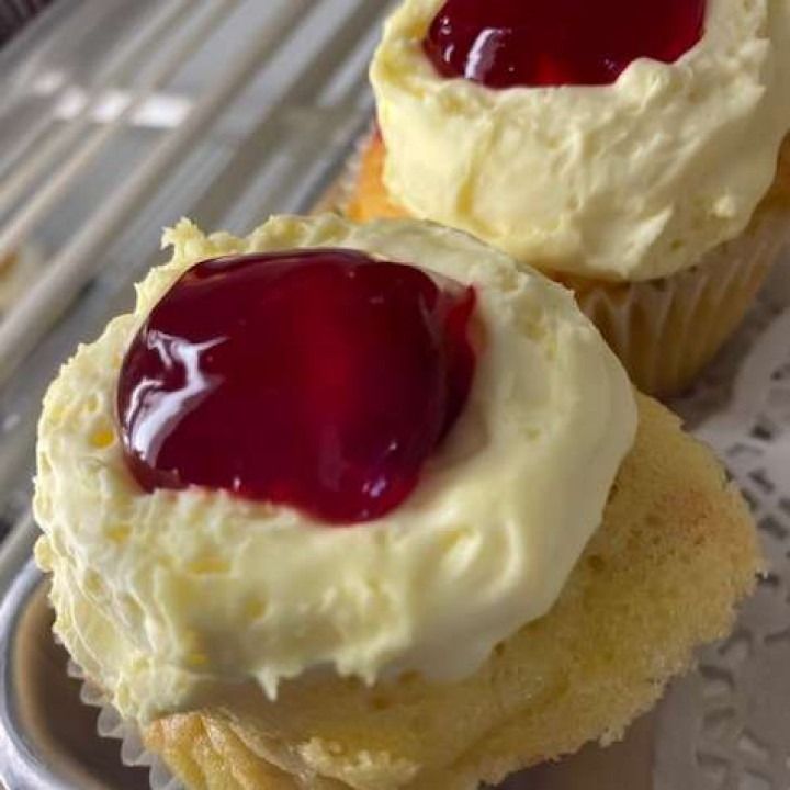 Cupcakes with yellow frosting and red jelly topping.