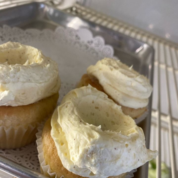 Cupcakes with white frosting on a silver tray, in a refrigerator.