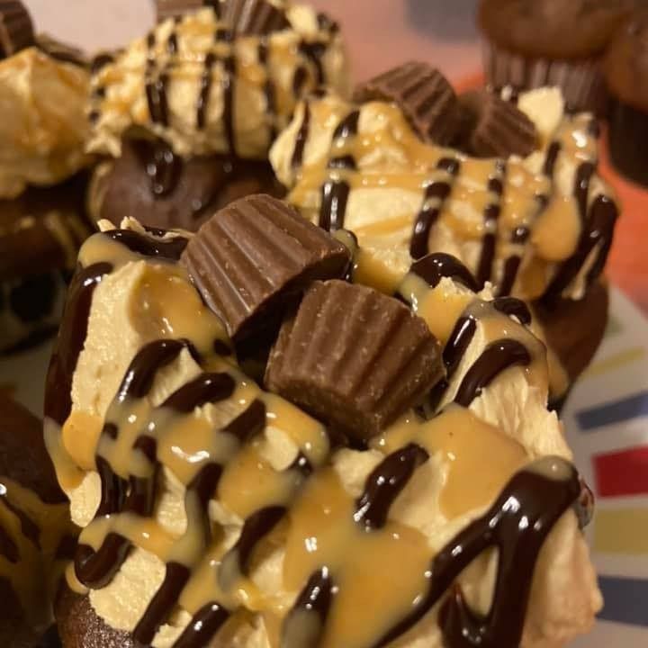 Close-up of chocolate cupcakes with peanut butter frosting, chocolate drizzle, peanut butter cups.