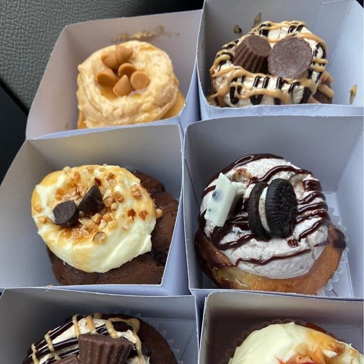 Six gourmet donuts in individual boxes, with various toppings: peanut butter cups, oreos, nuts, and frosting.