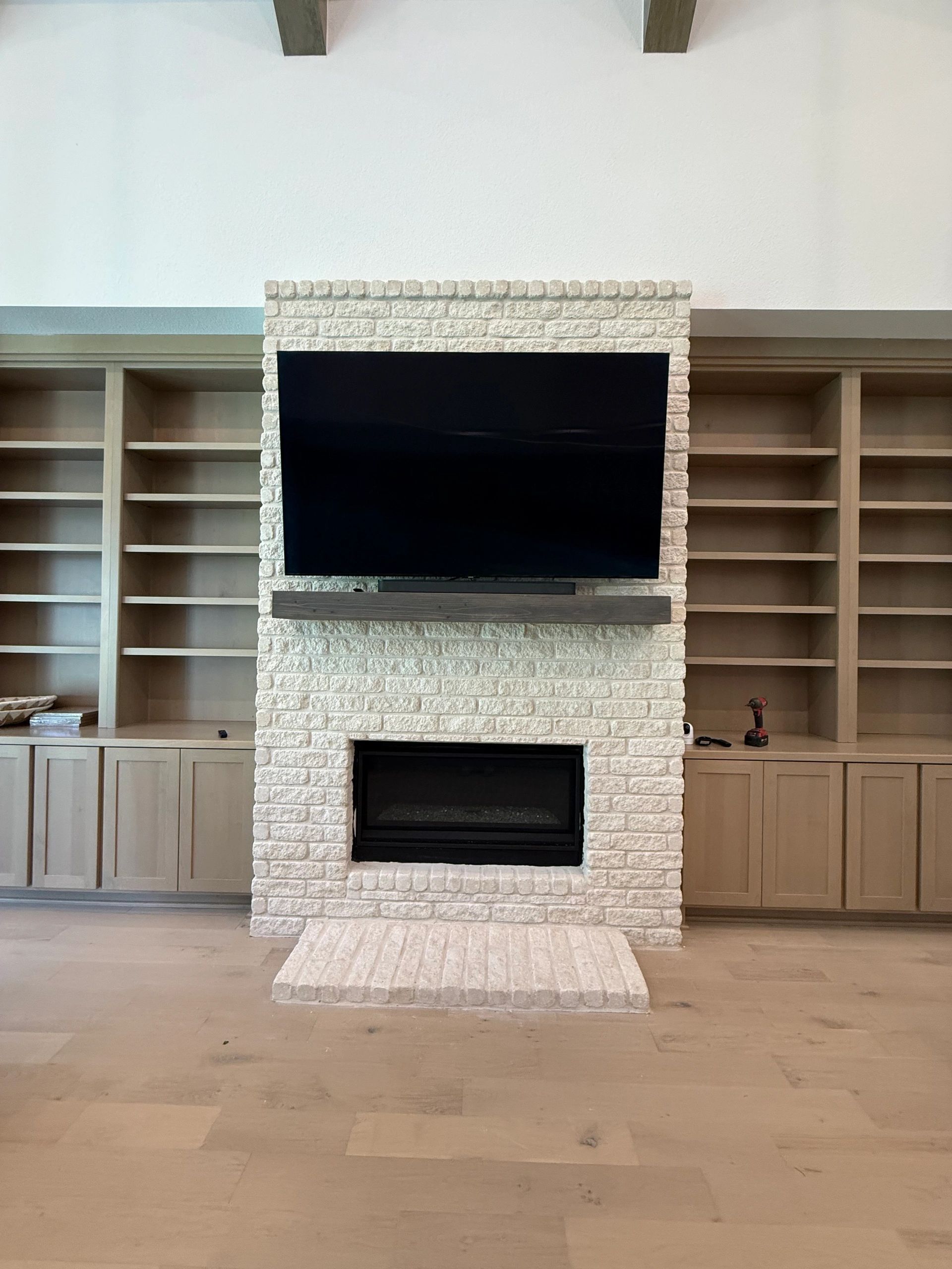 Living room with built-in cabinets, a stone fireplace, and a large mounted TV