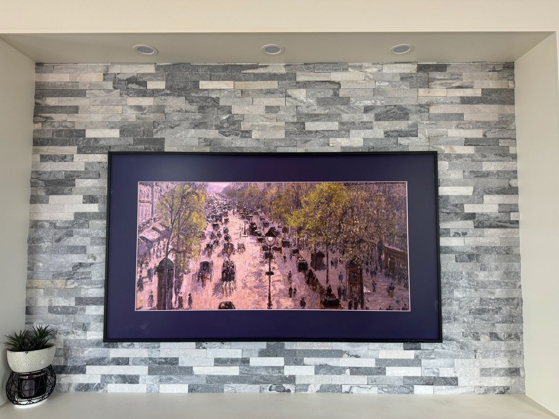 Wall-mounted TV displaying a pink-toned forest scene on a stone accent wall