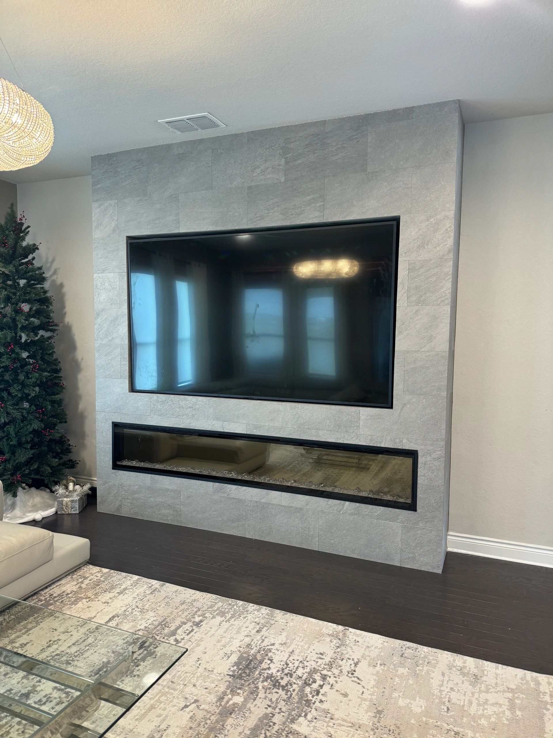 Living room with wall-mounted TV above long electric fireplace on a textured gray accent wall