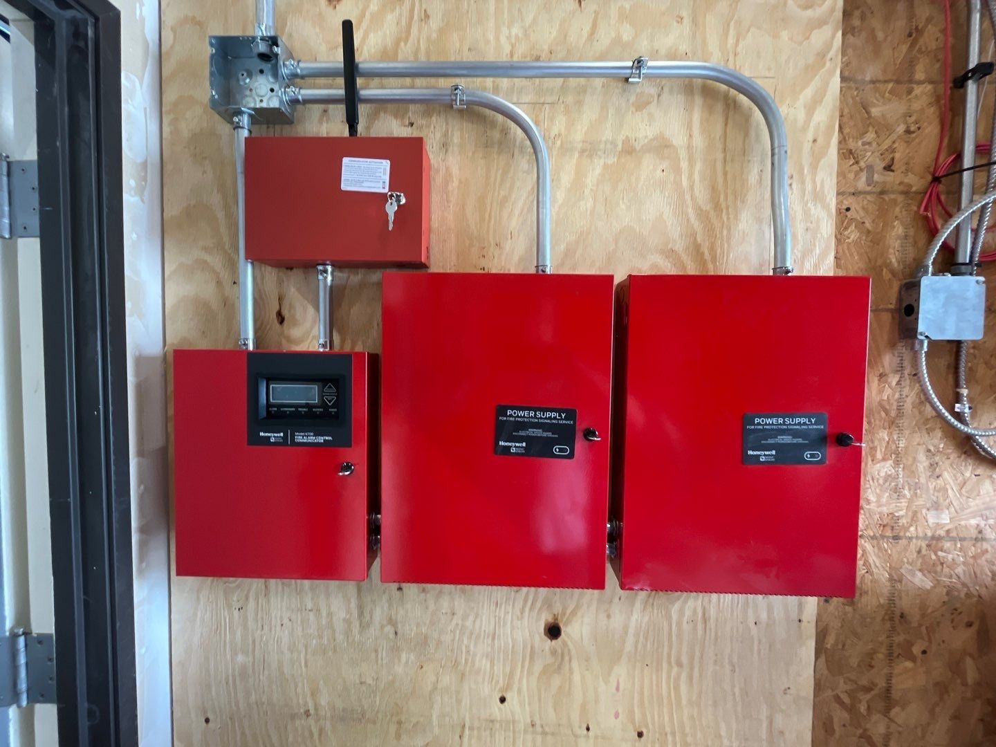 Red electrical equipment on wooden wall. Includes boxes and conduit.