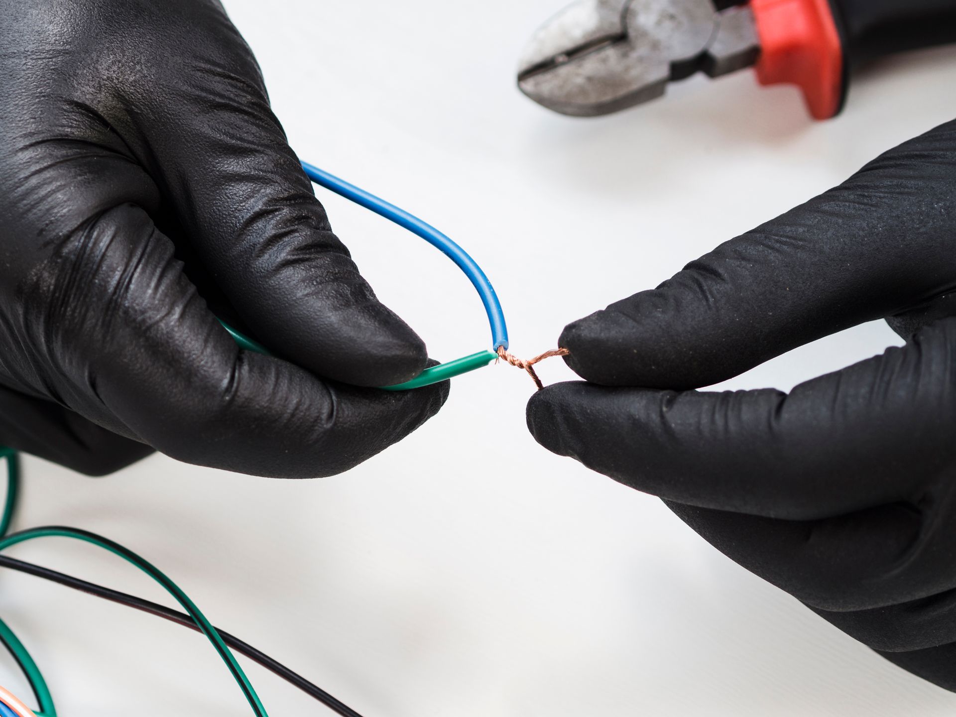 A person wearing black gloves is working on electrical wires.