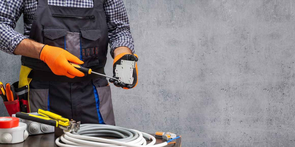 An electrician is working on a socket with a screwdriver.