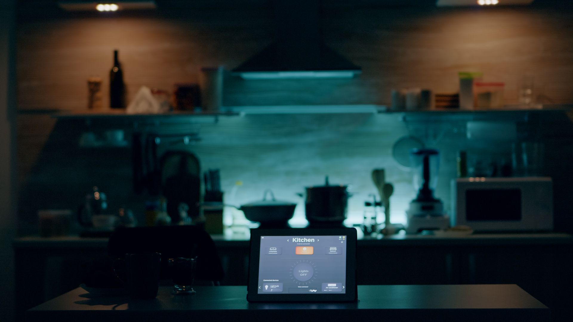 A tablet is sitting on a kitchen counter in the dark.