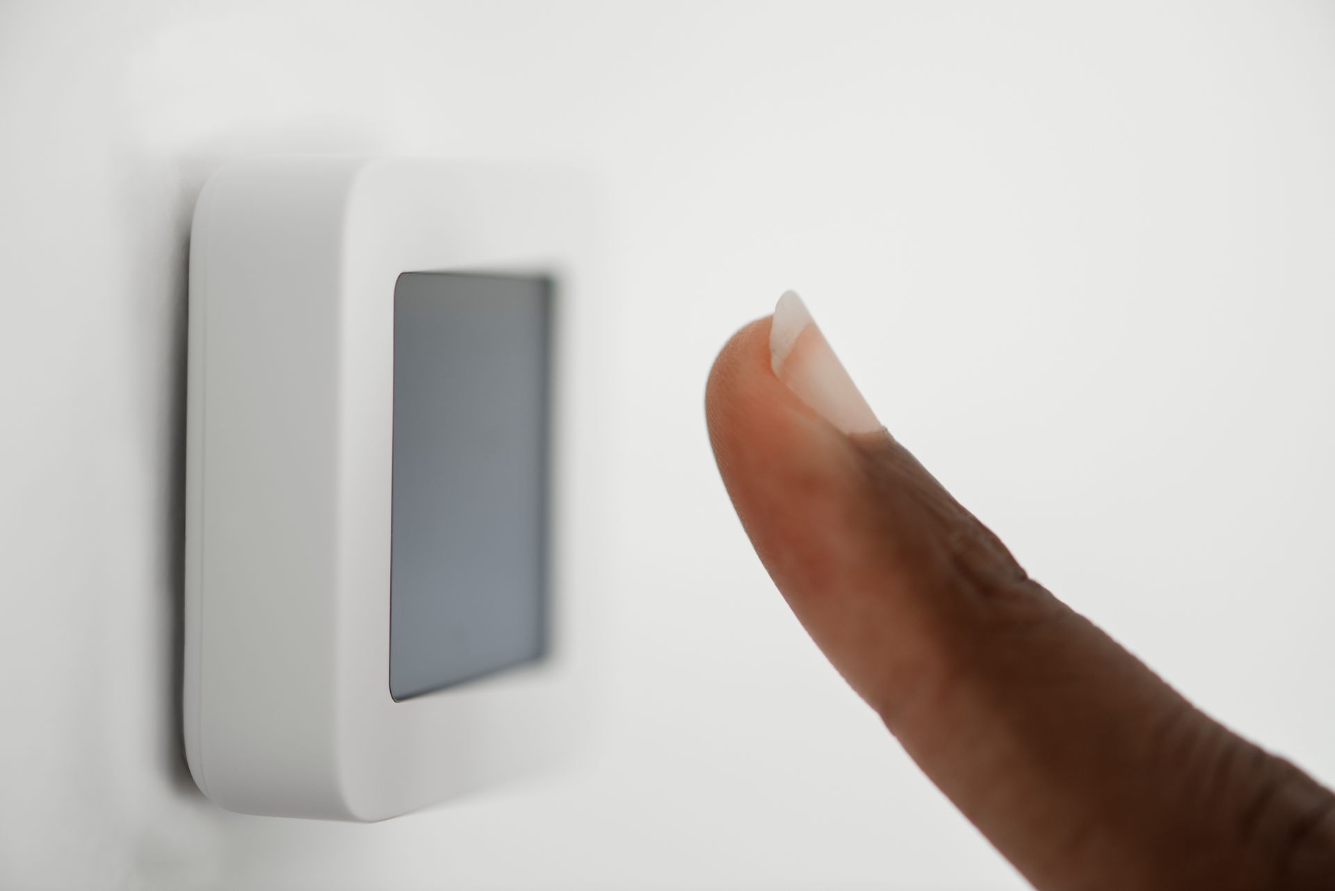 A person is pressing a button on a thermostat.