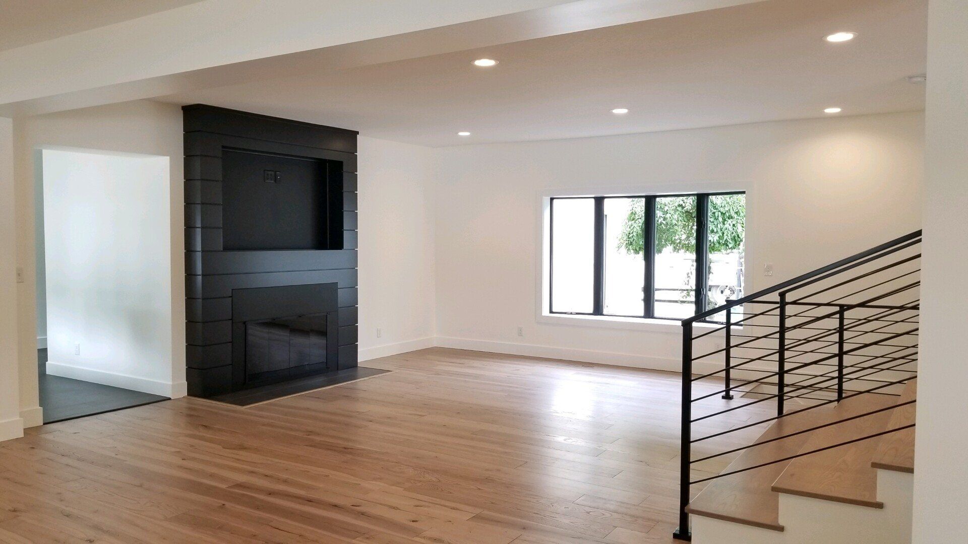 An empty living room with a fireplace and stairs.