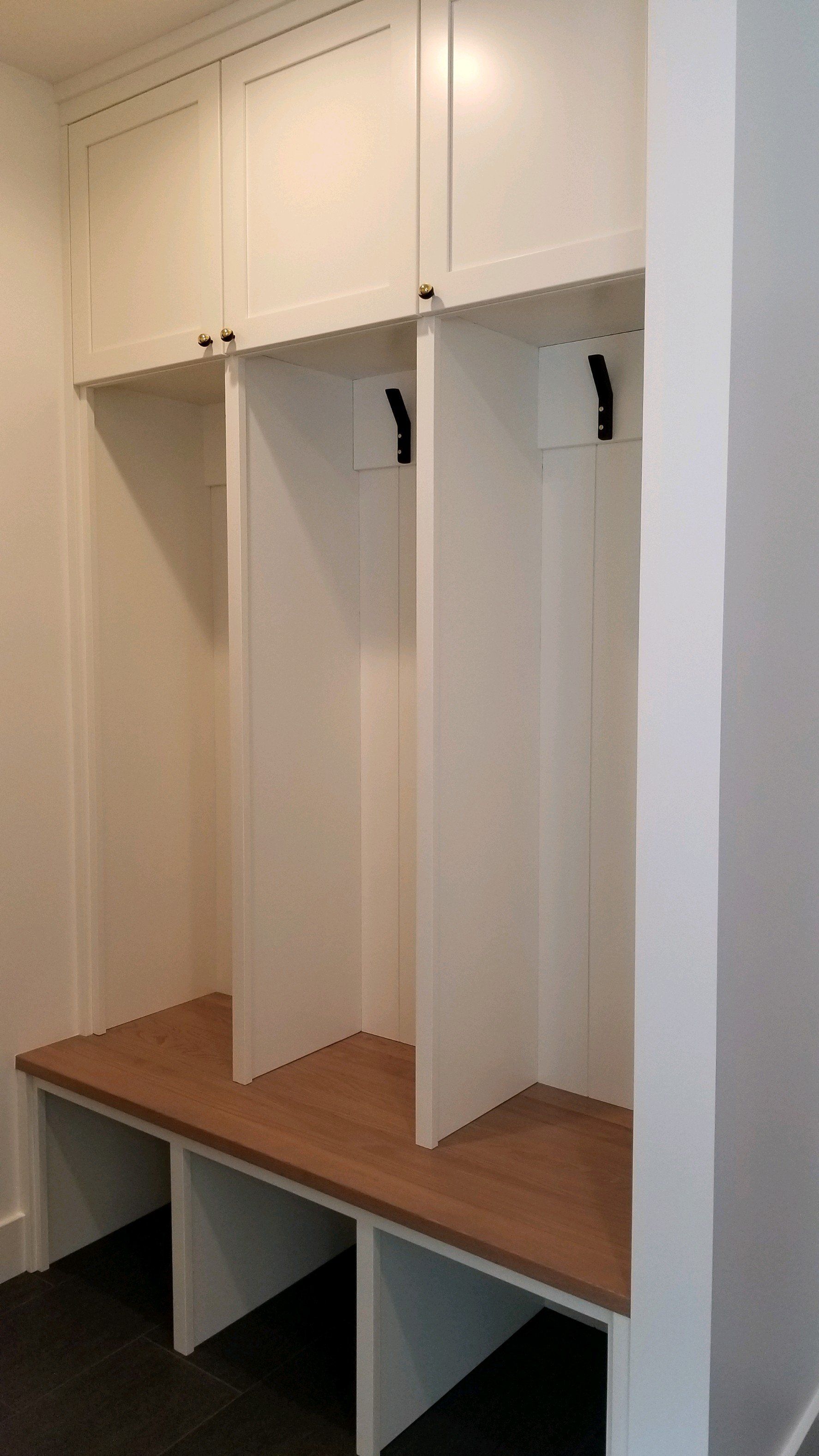 A mud room with white cabinets and wooden benches.