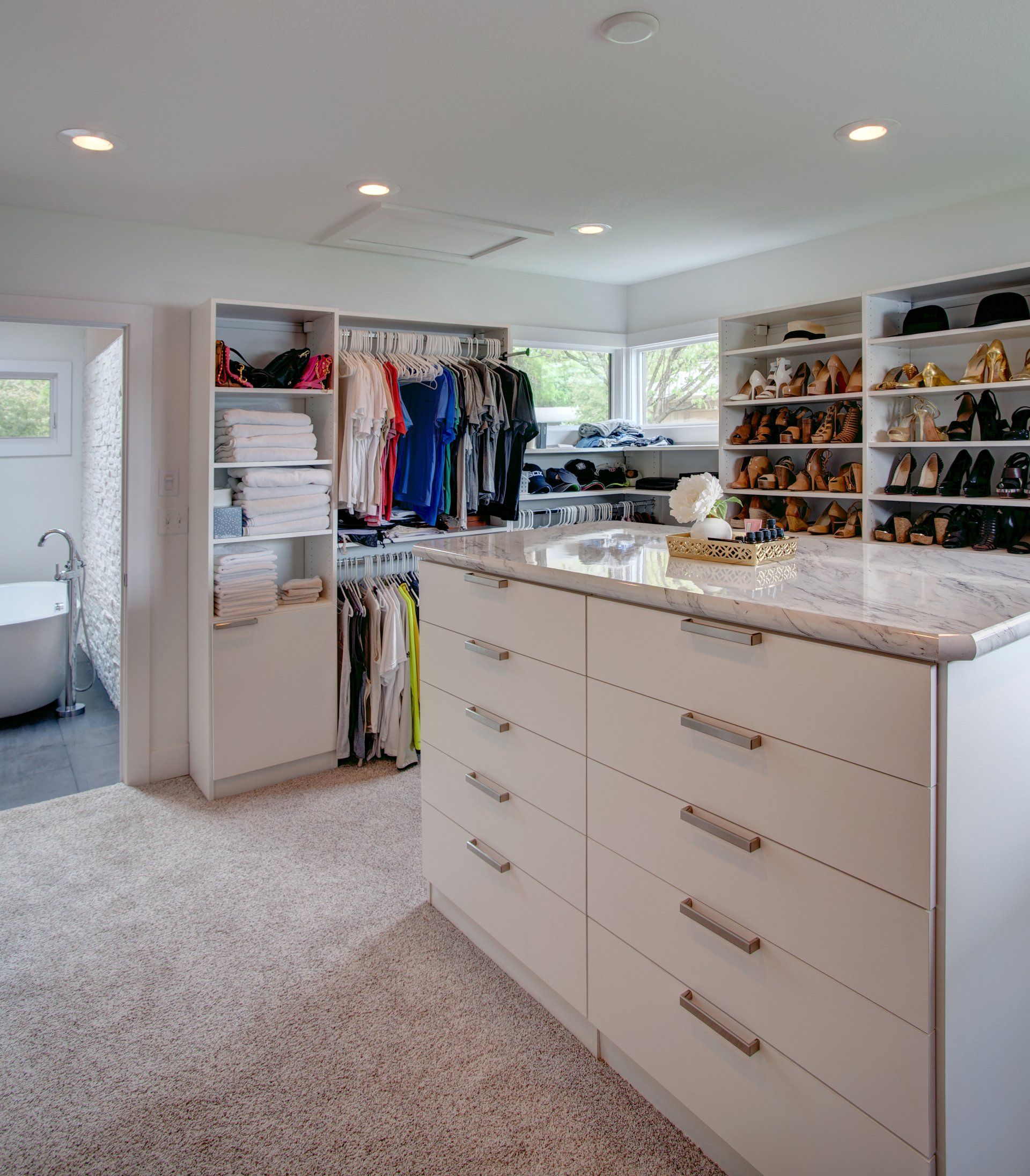 A walk in closet filled with lots of clothes and shoes.