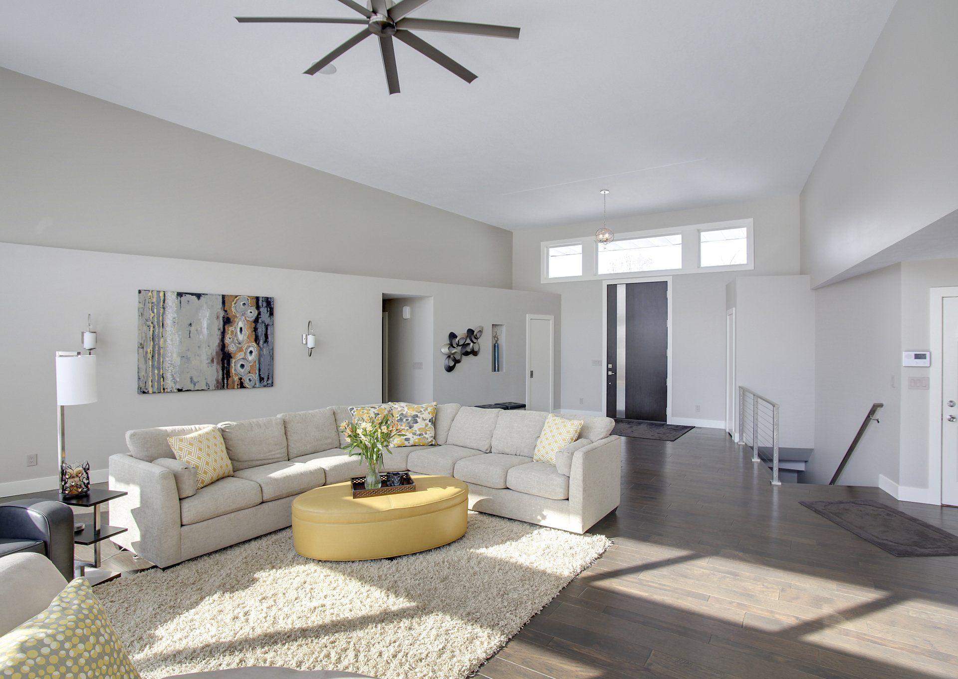 A living room with a large sectional couch and a yellow coffee table