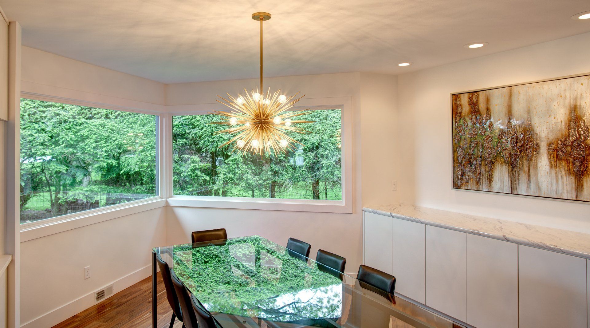 A dining room with a green table and chairs and a chandelier hanging from the ceiling.