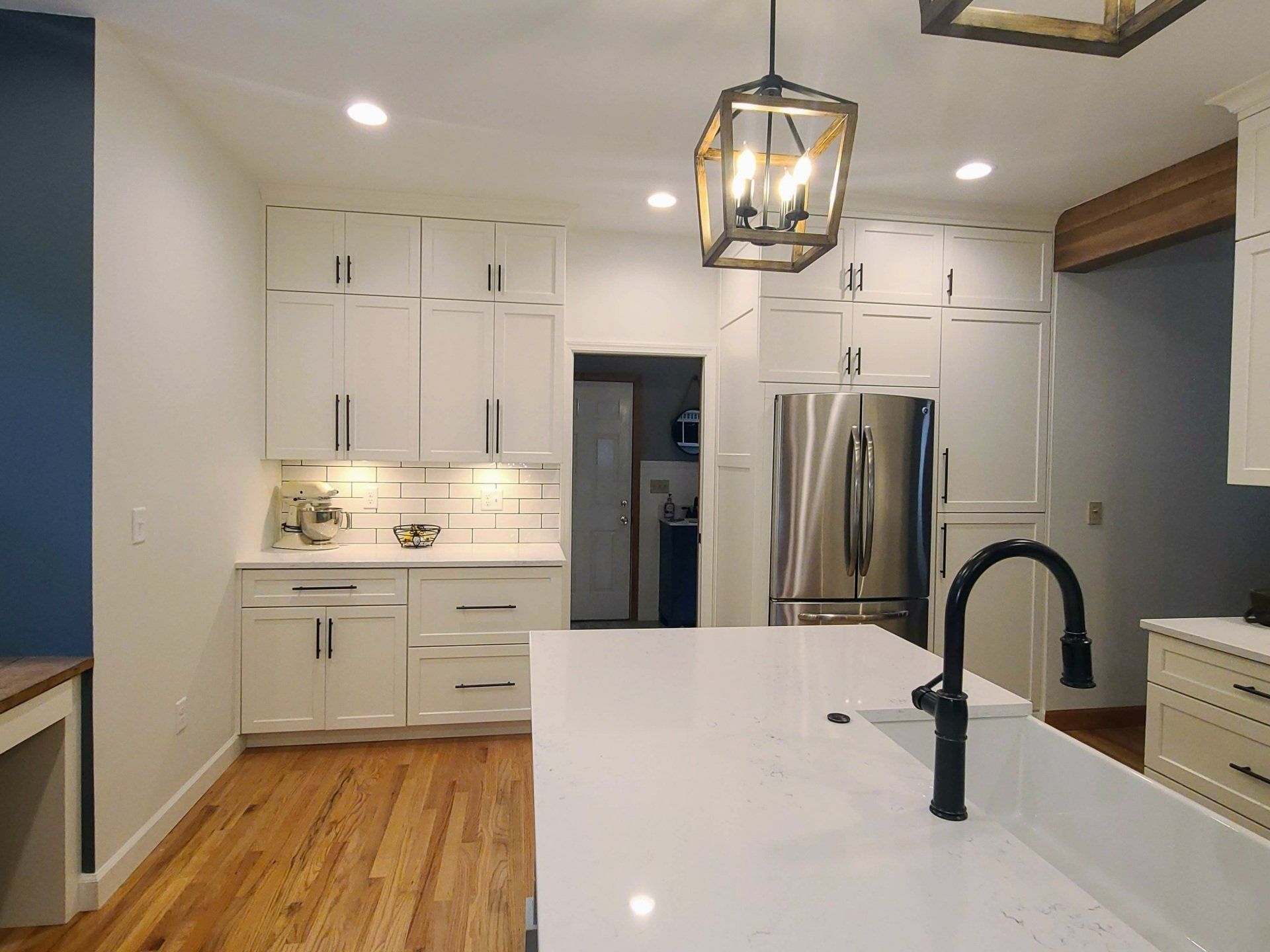 A kitchen with white cabinets , a stainless steel refrigerator , a sink , and a large island.