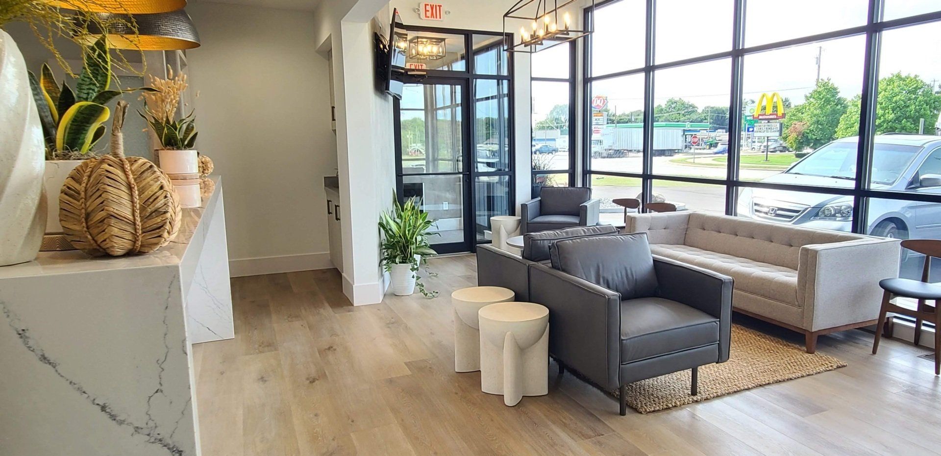 A living room with a couch , chairs , tables and a large window.