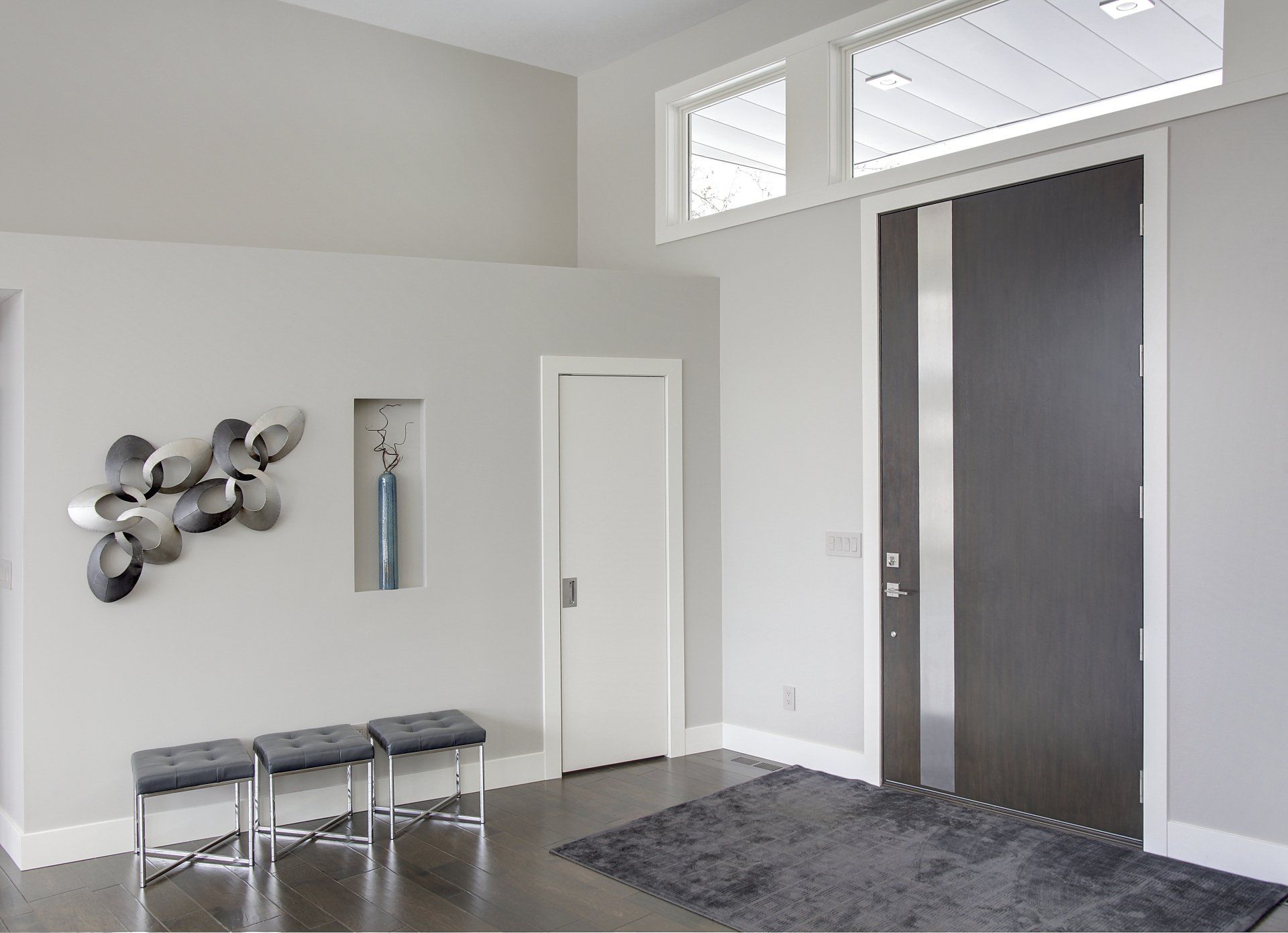 A hallway with a black door and a gray rug