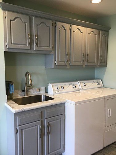 A laundry room with a washer and dryer , sink and cabinets.