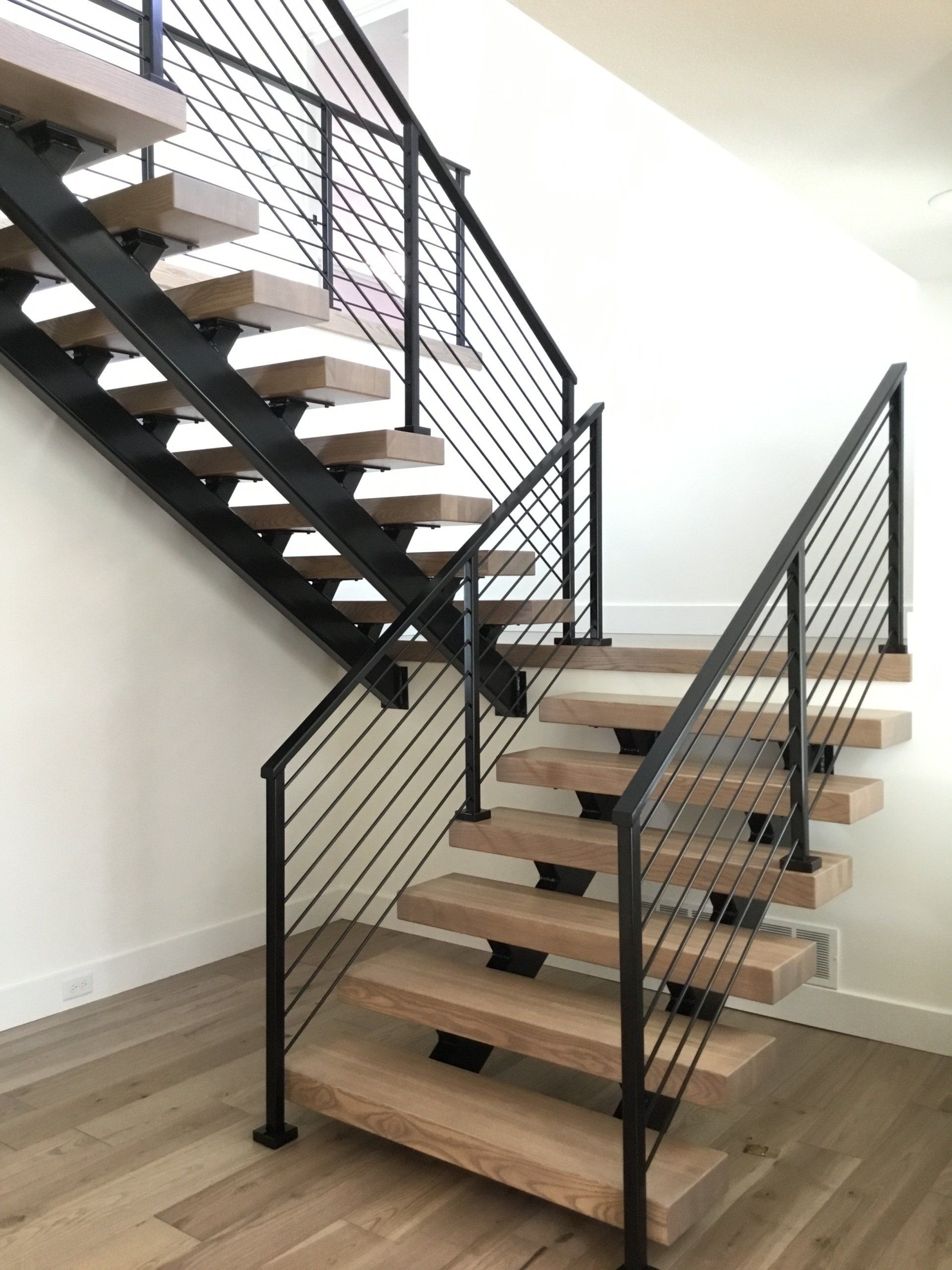 A wooden staircase with a black railing in a room.