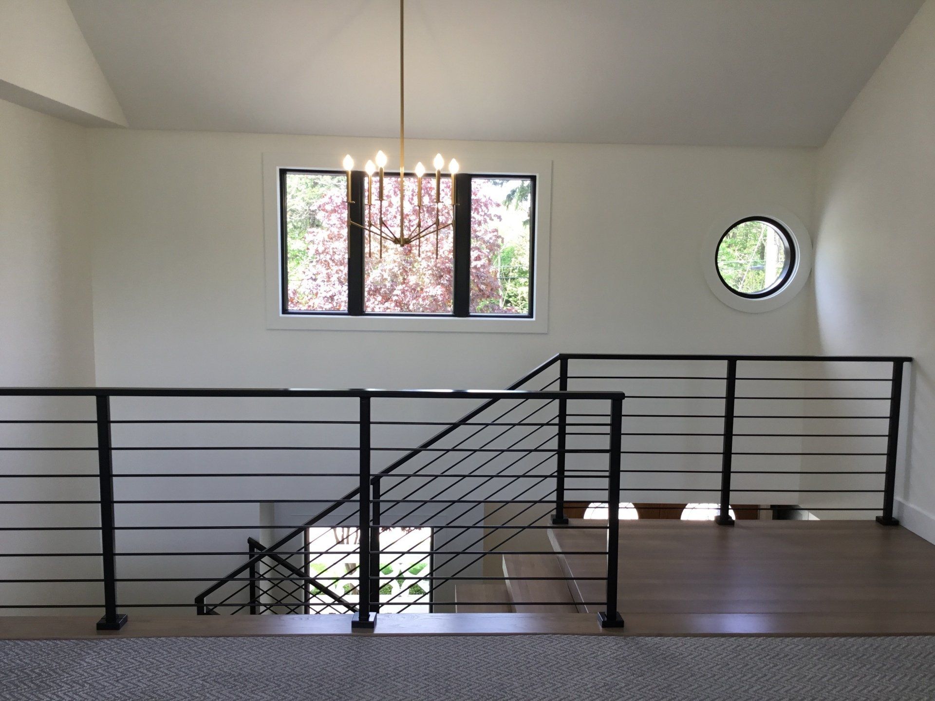 A staircase with a black railing and a round window