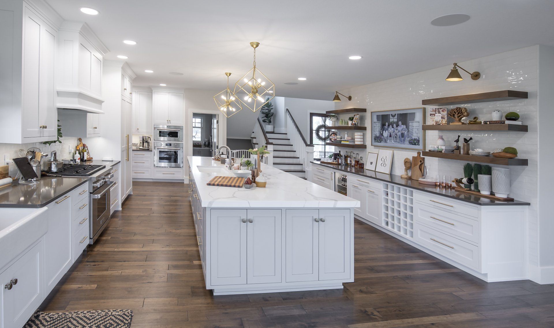 A large kitchen with white cabinets and stainless steel appliances and a large island in the middle.