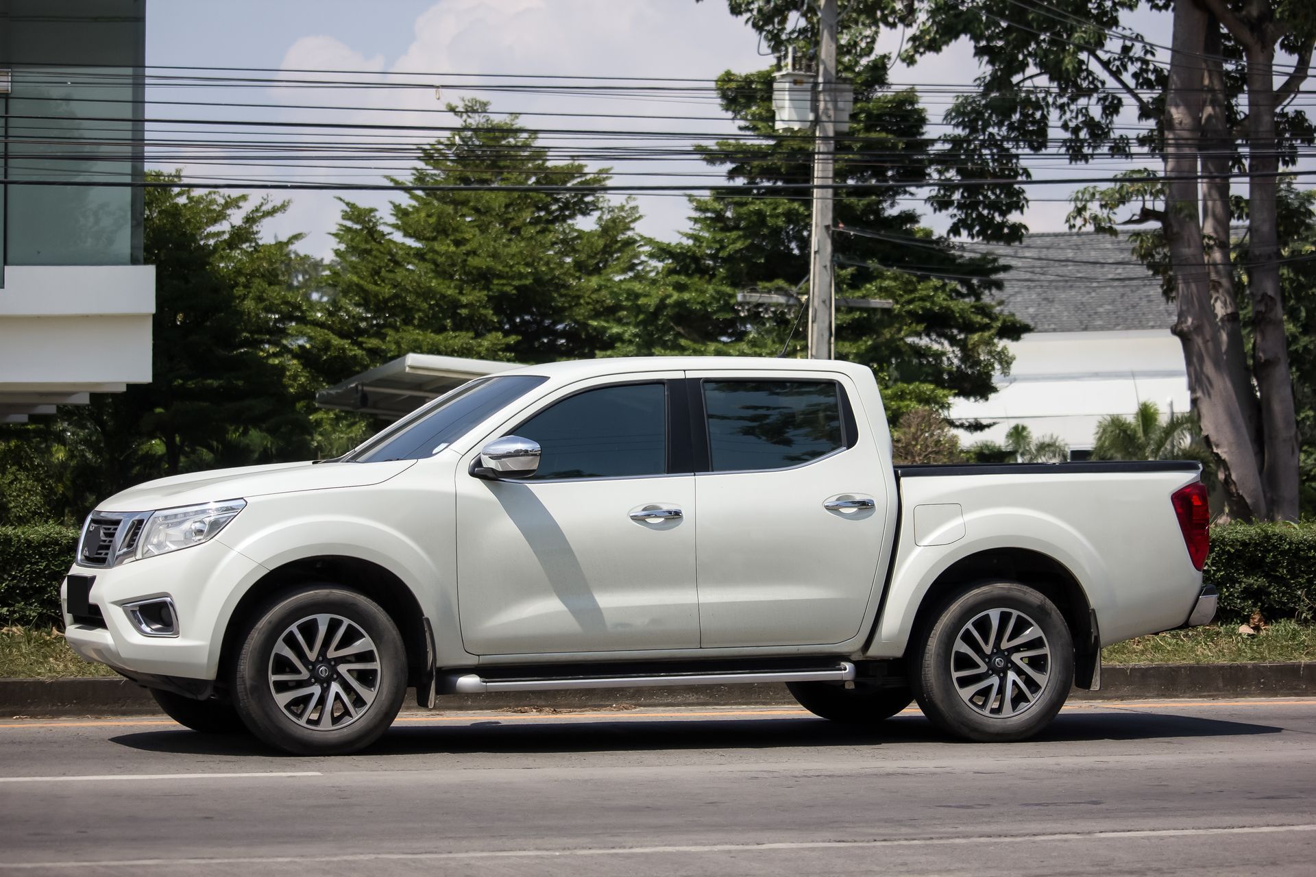 A white truck with a utility body, a dump truck, and a black stake body parked on a road.