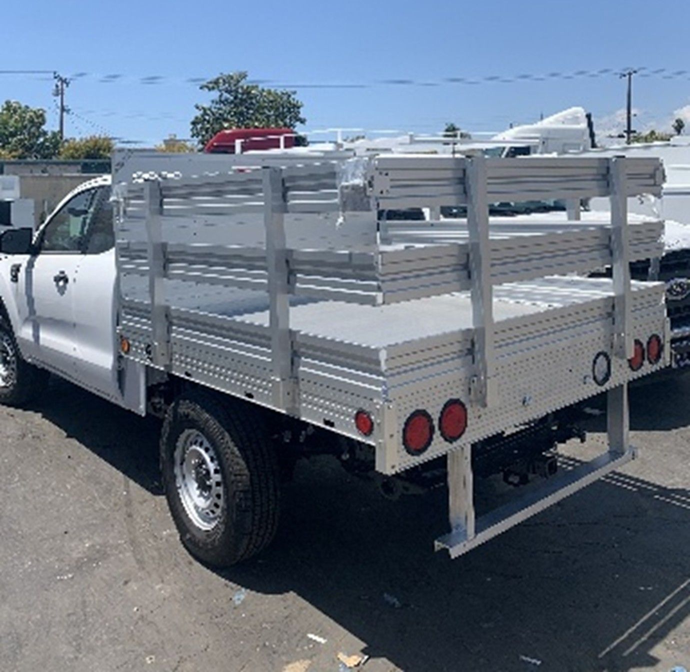 White stake bed truck with metal sides.