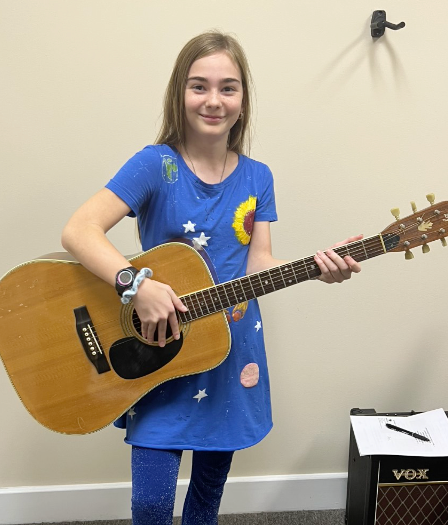 A young girl is playing a violin in a room.