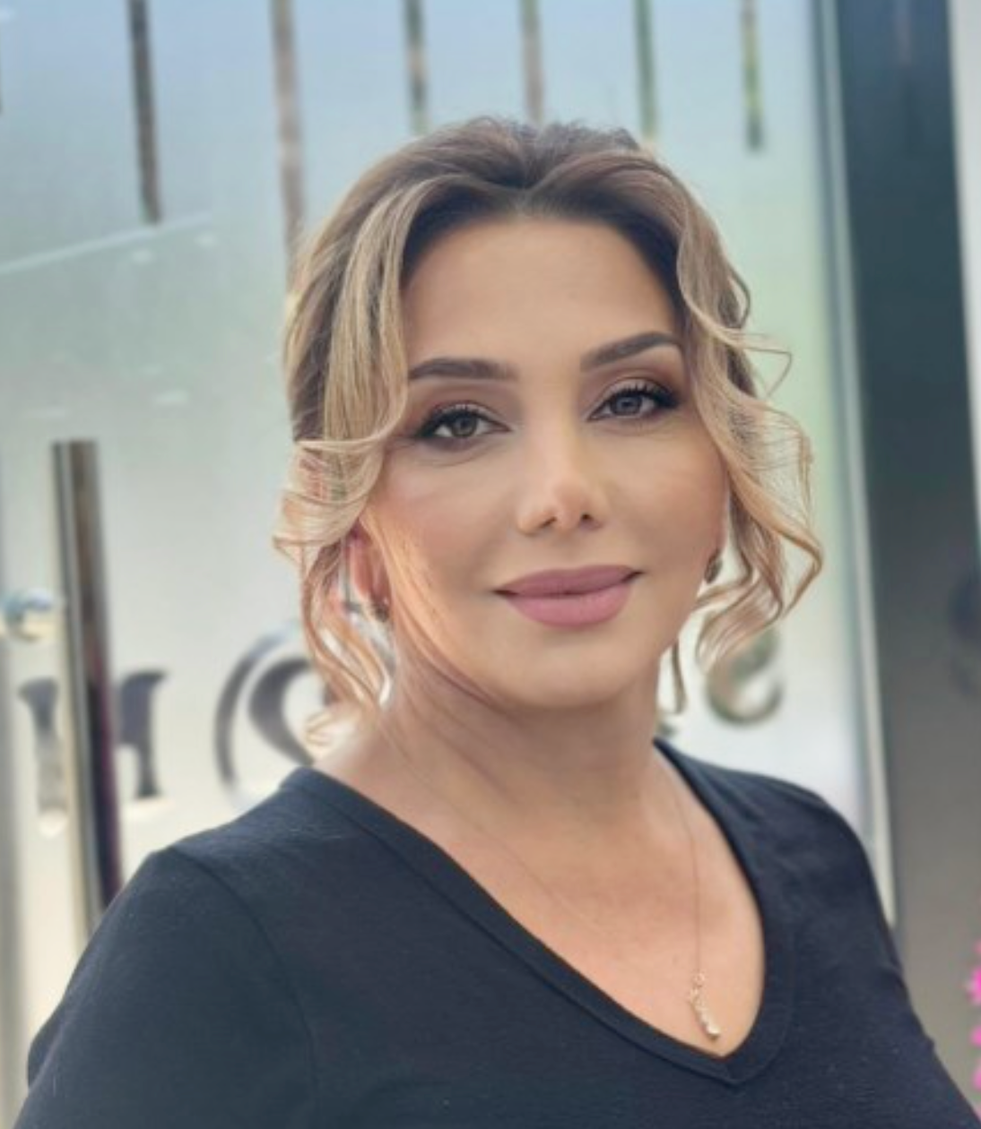 A woman wearing a hat and a floral dress is smiling.