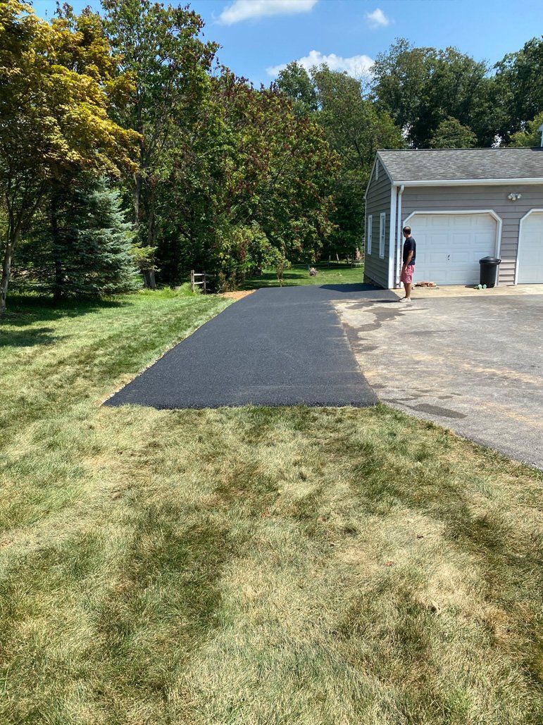 A man is walking down a driveway next to a garage.