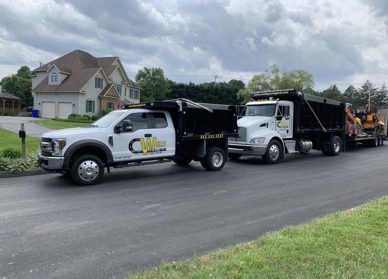 Two dump trucks are parked on the side of the road
