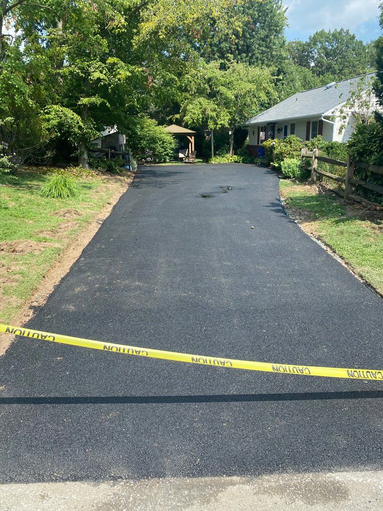A driveway with a yellow tape that says caution on it