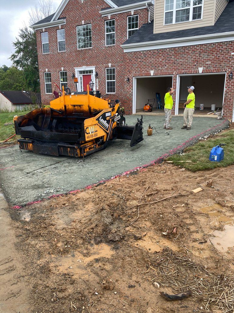 A yellow tractor is sitting in front of a brick house