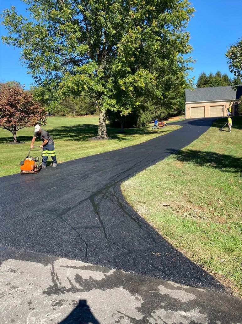 A man is working on a driveway in front of a house.