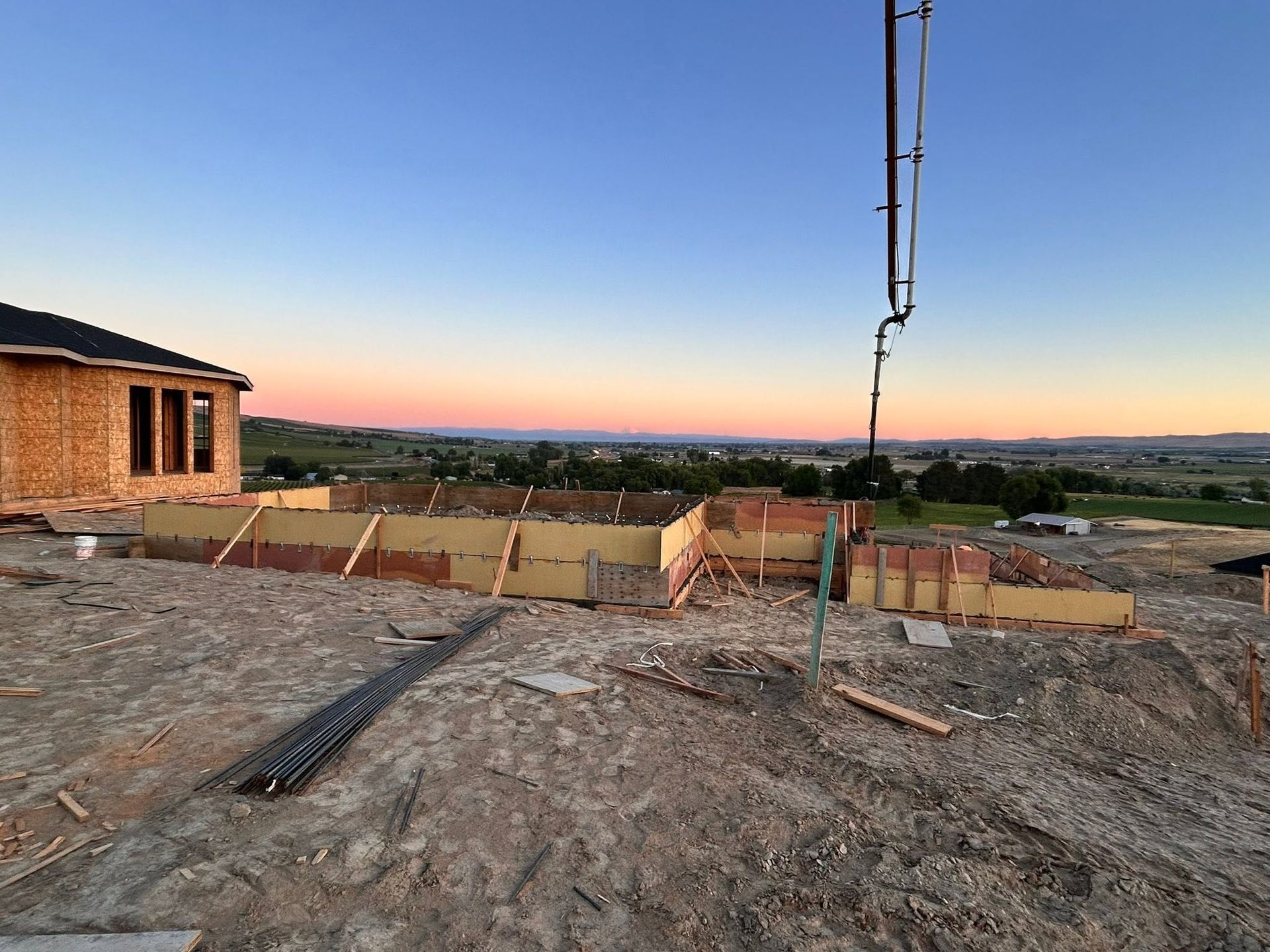 Construction site at sunset with foundation forms and a view over a valley under a clear sky