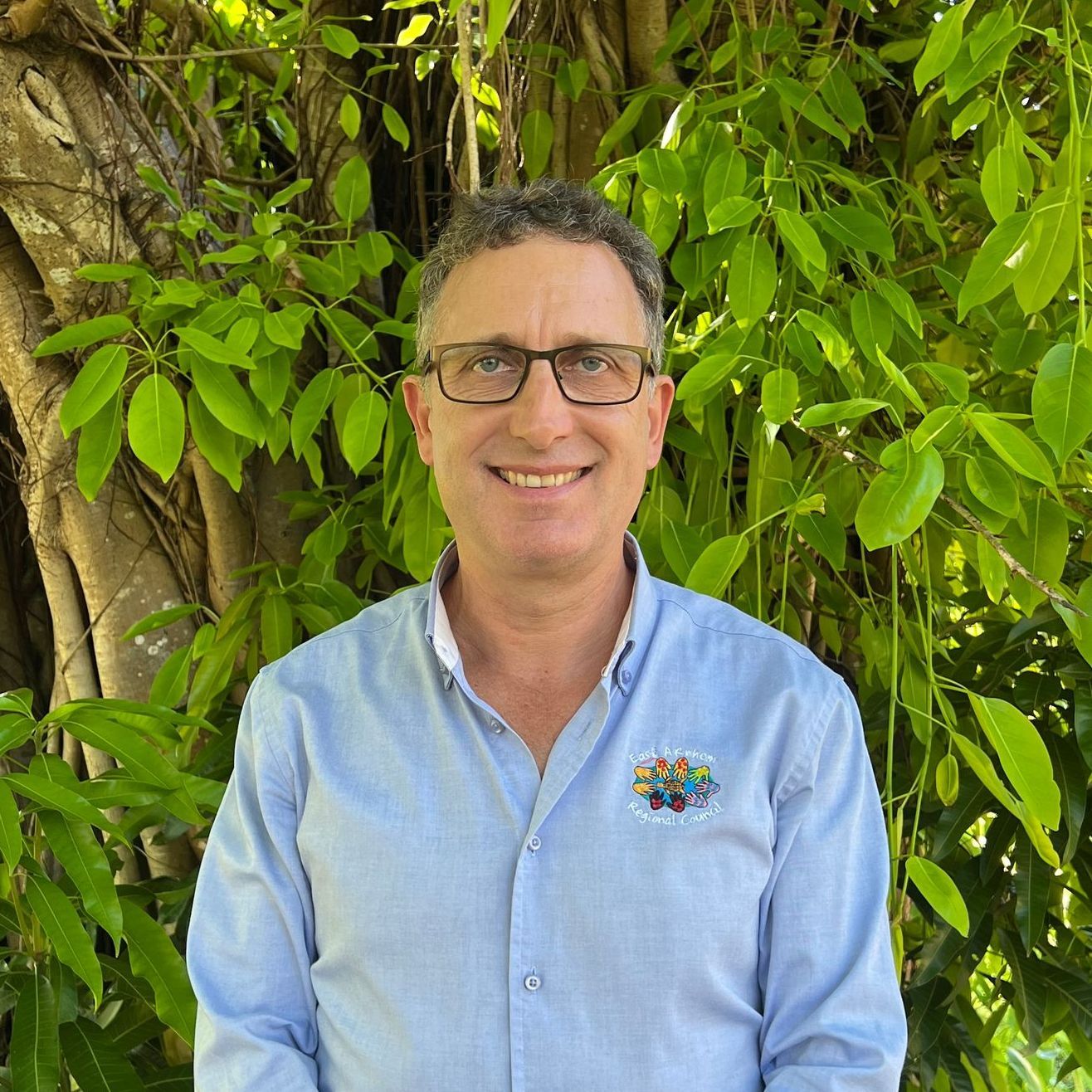 A man wearing glasses and a light blue dress shirt. 