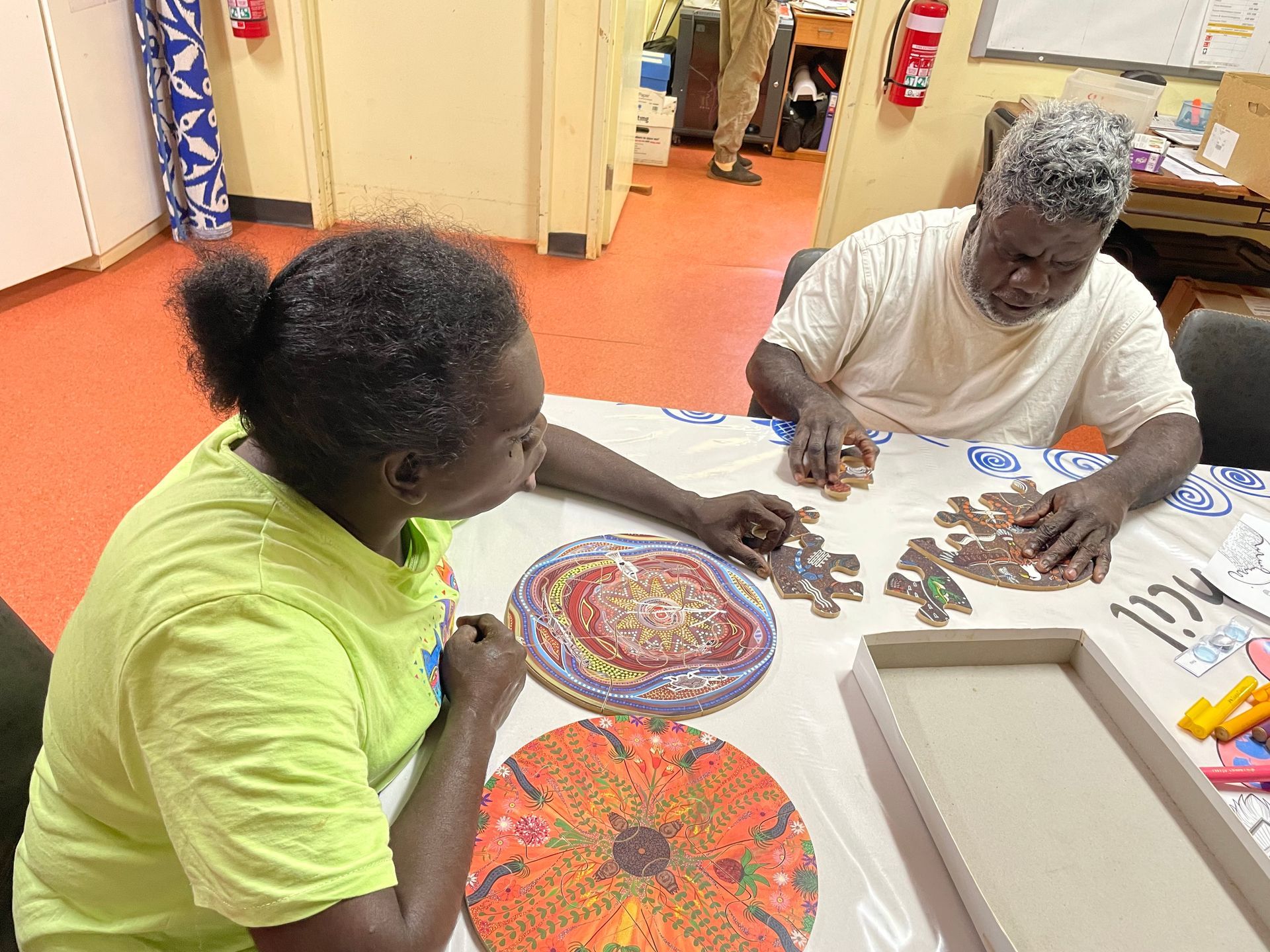 A man and woman sit at a table working on puzzles