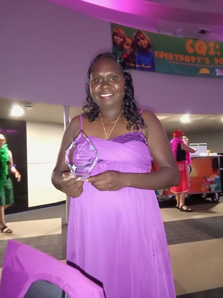 A woman smiling and holding an award