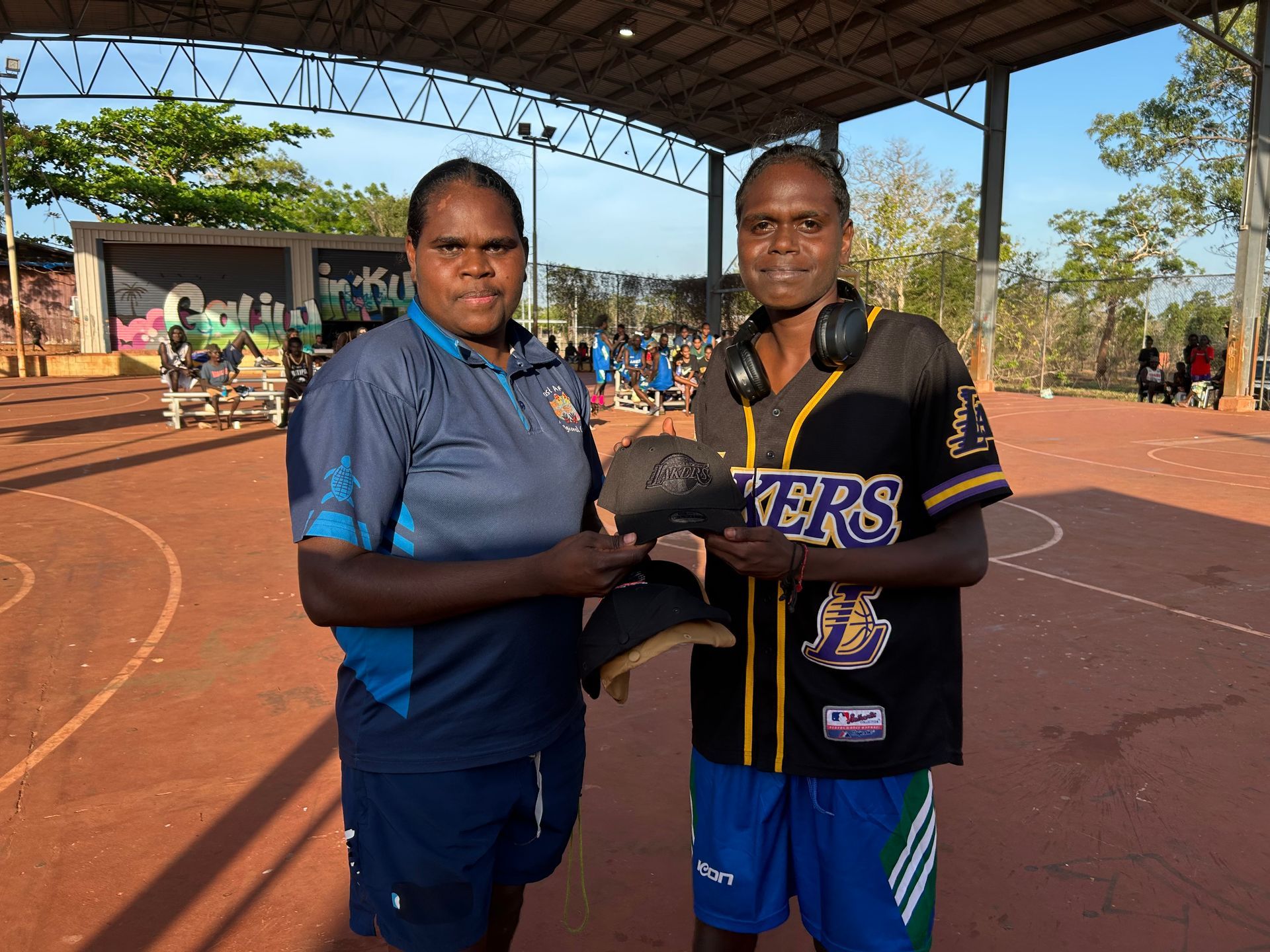 Two people stand together. One is giving the other a cap.