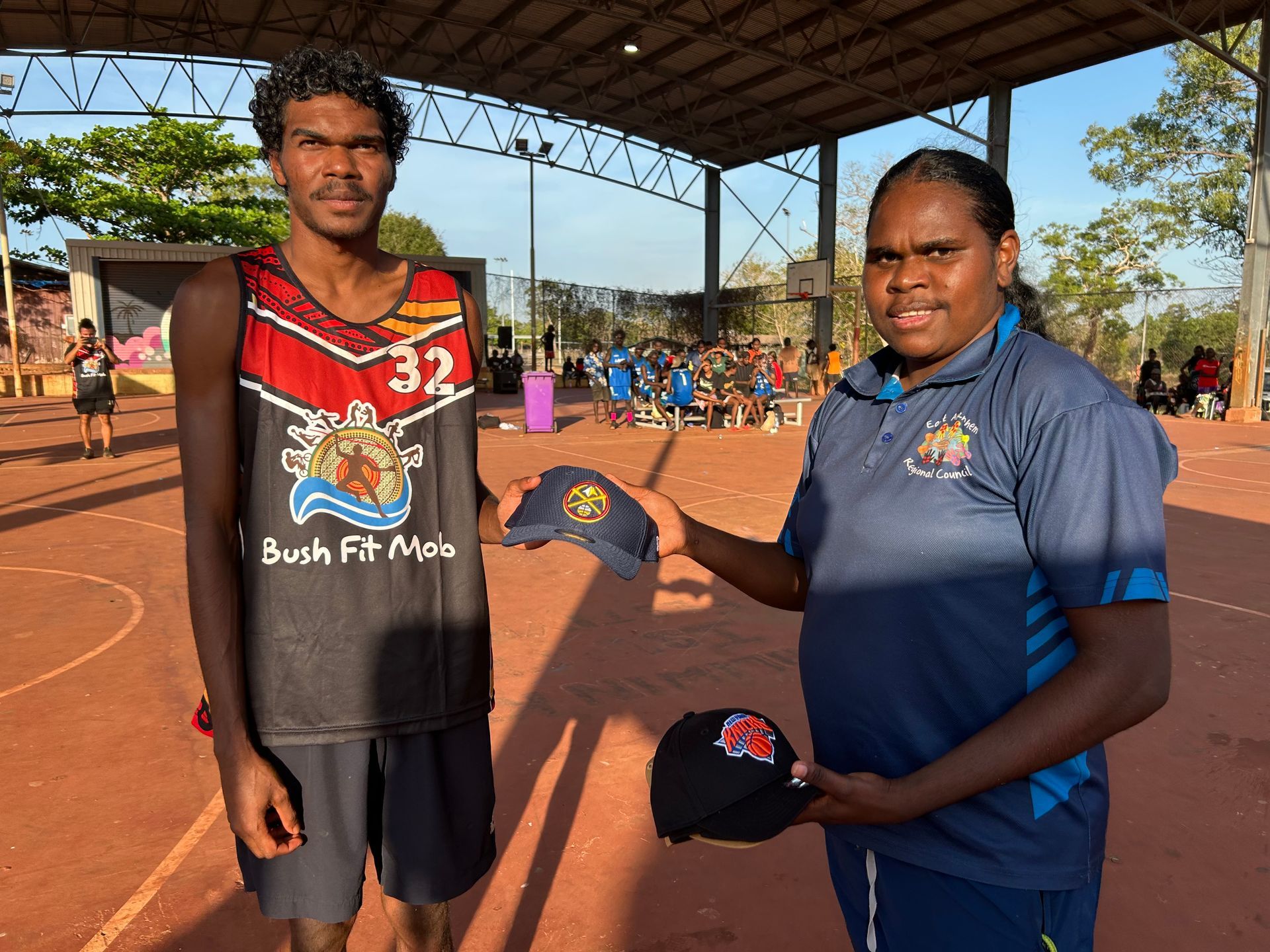 Two people stand together. One is giving the other a cap.