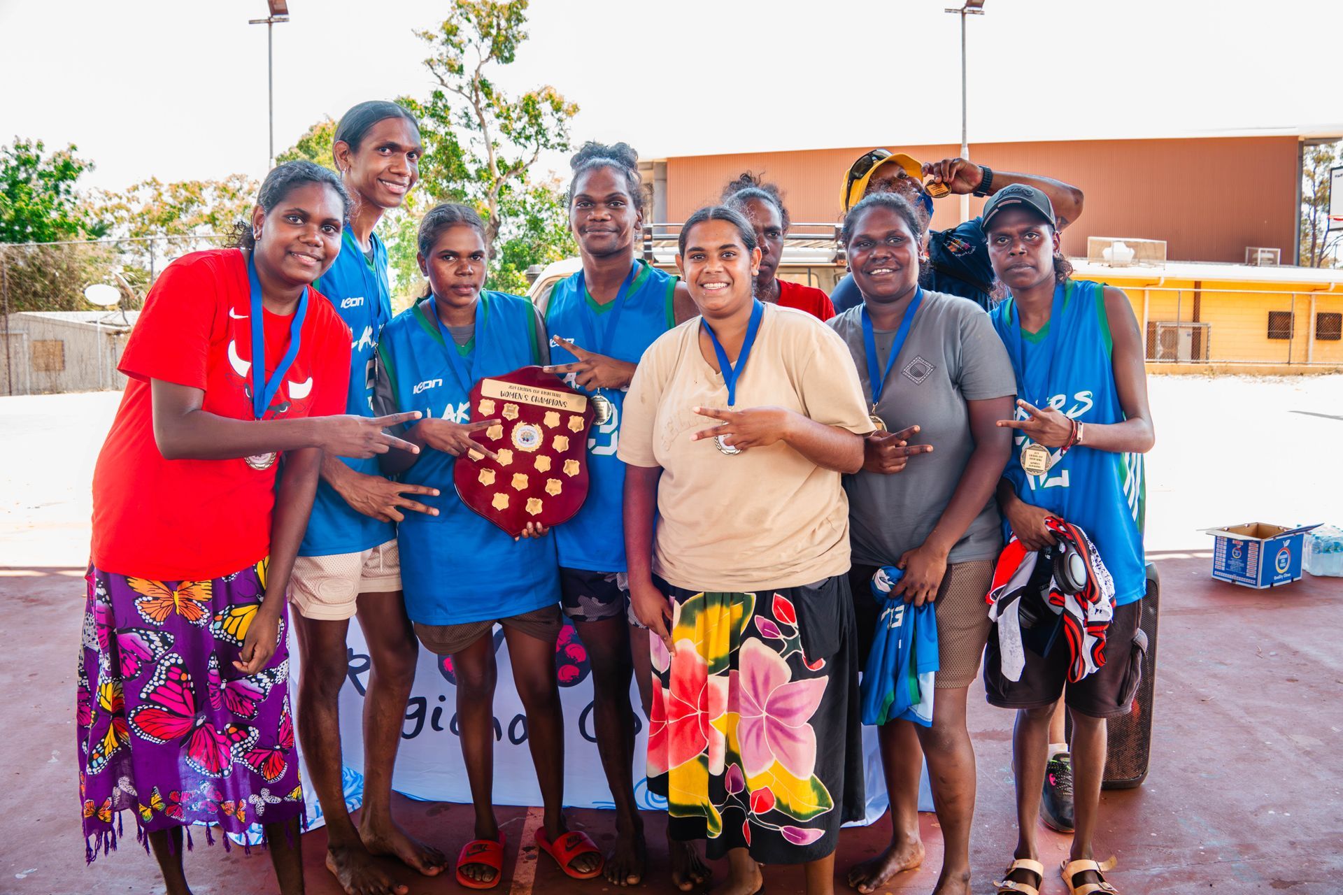 A group of people gather together. The person in the middle holds a trophy