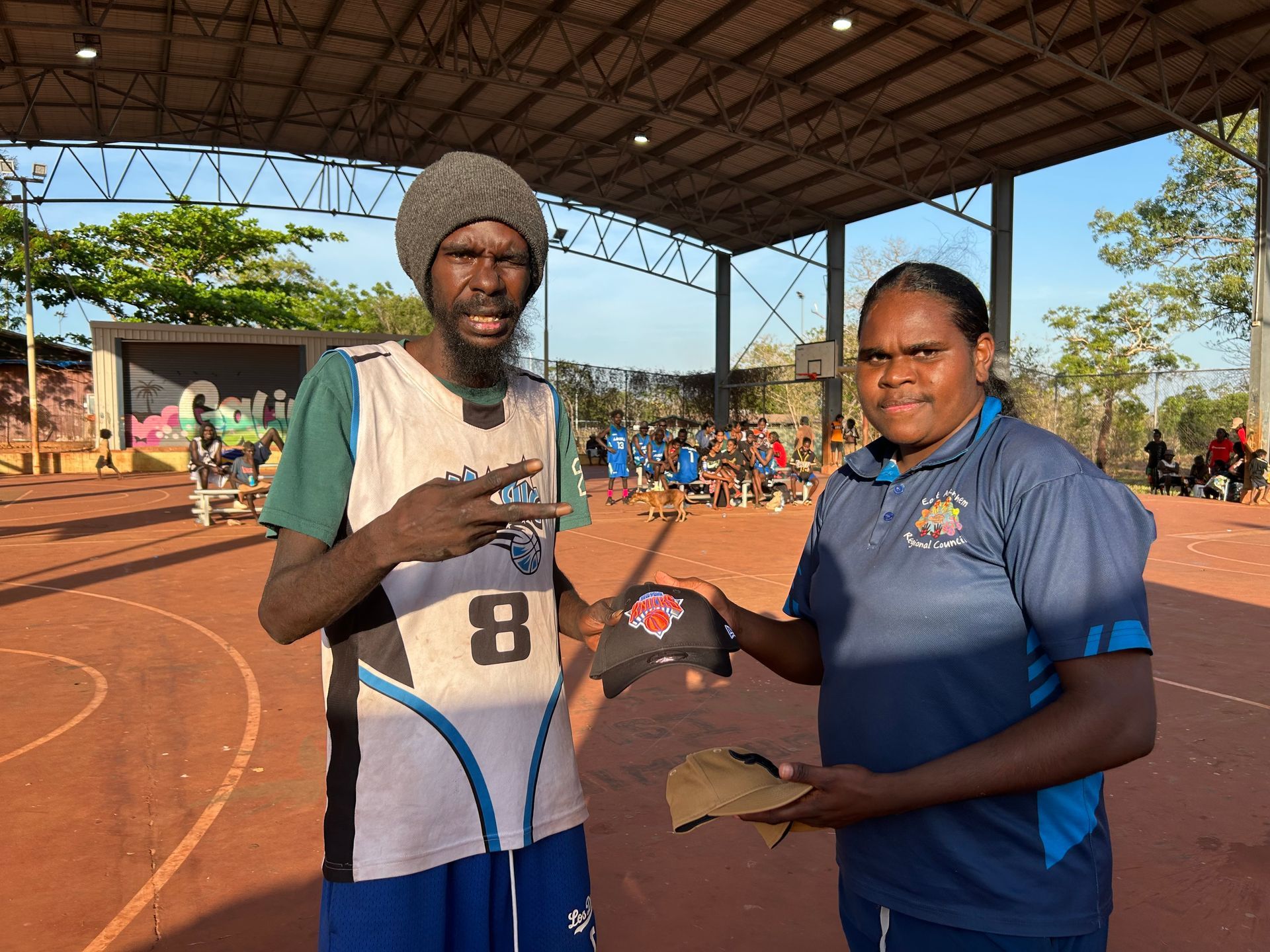 Two people stand together. One is giving the other a cap.