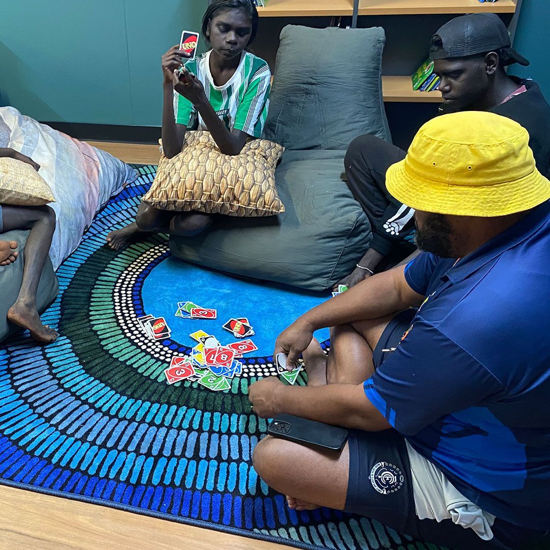 A Coordinator with three kids playing a card game.