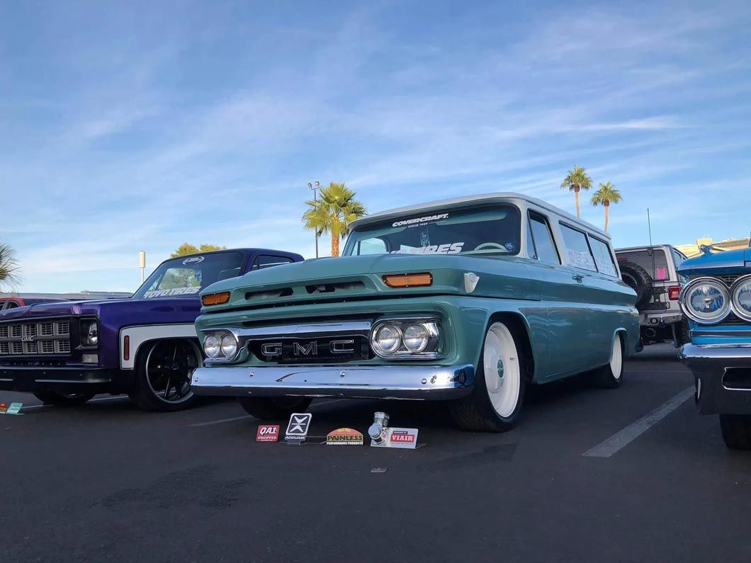 A row of old cars are parked in a parking lot.