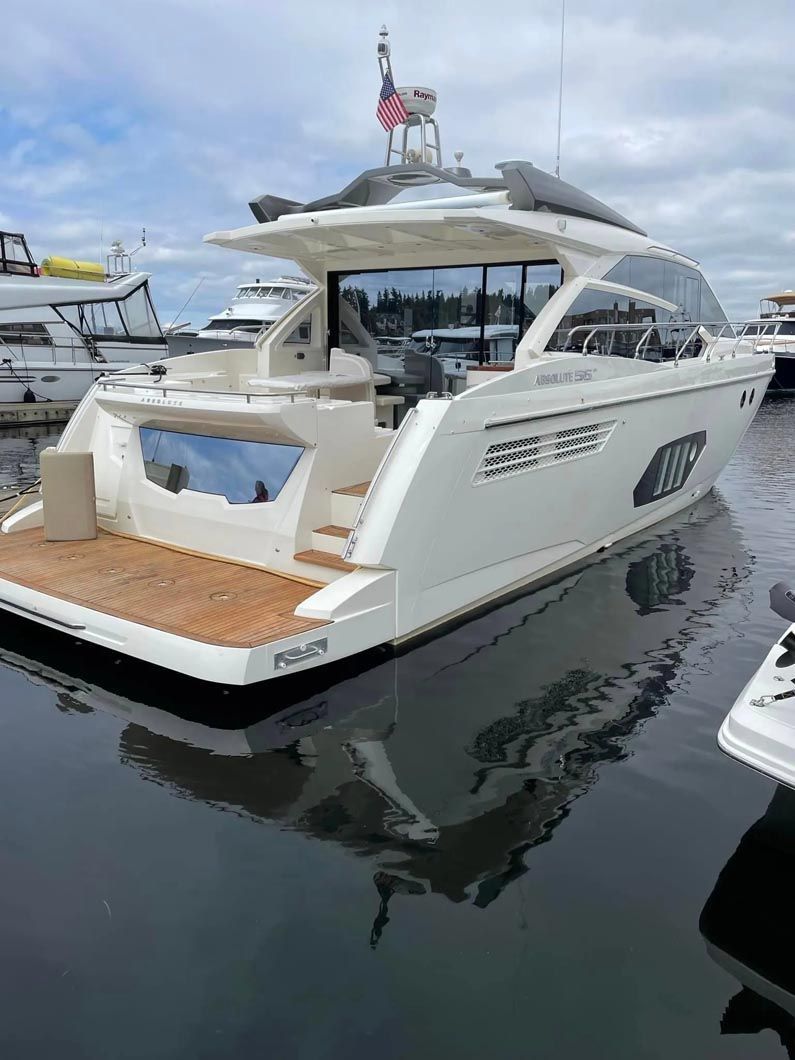 A large white yacht is docked in a marina.