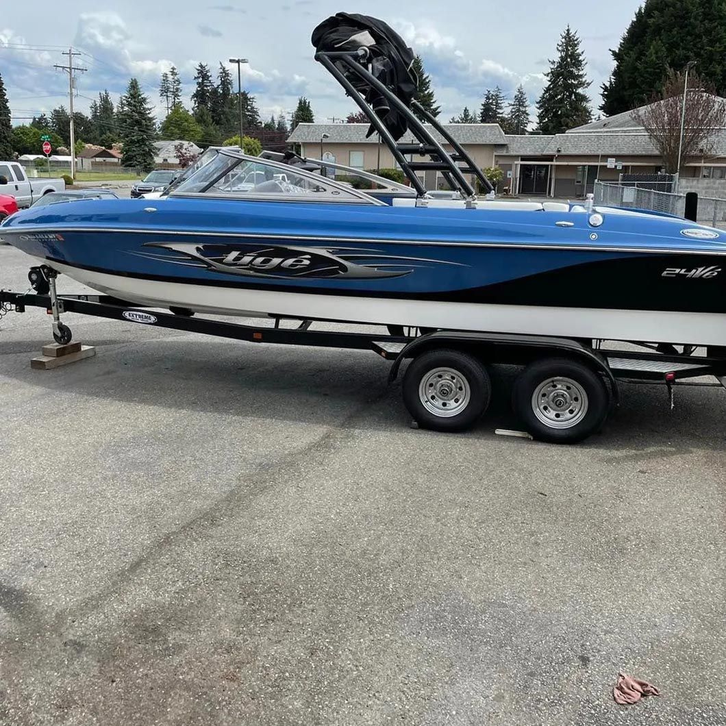 A blue boat is parked on a trailer in a parking lot.