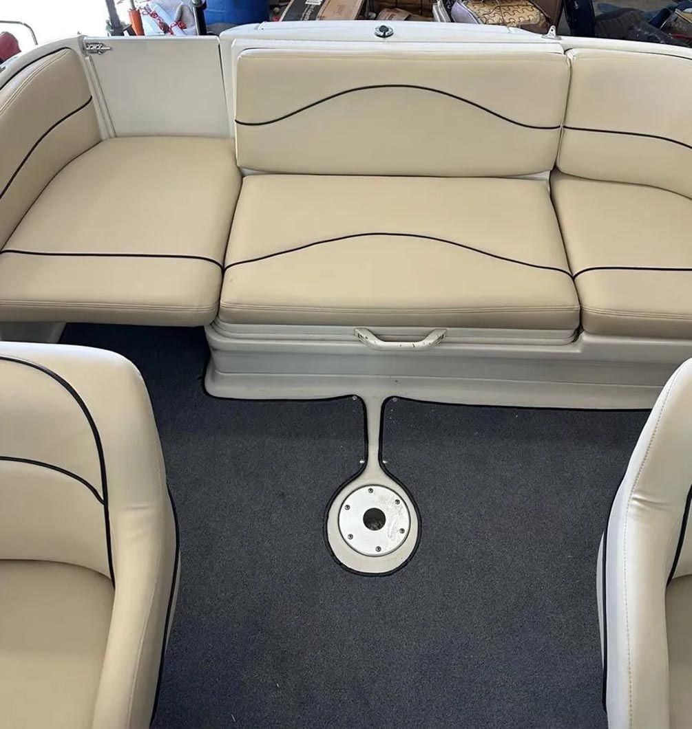 The inside of a boat with a couch and chairs.